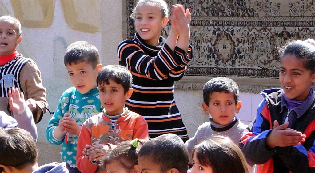 Happy children reacting to a clown magic show performed in a rural refugee village, Jordan 