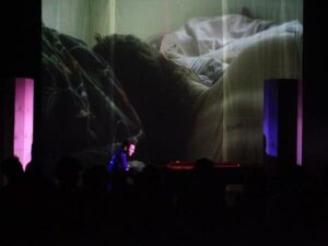 Composer Dan Thorpe playing piano in front of a projection