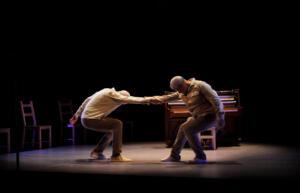 two men holding their hands and squatting down on the stage