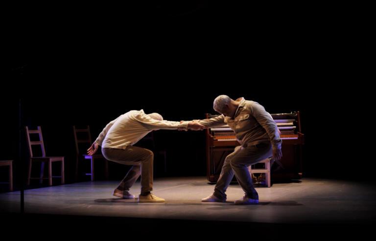 two men holding their hands and squatting down on the stage